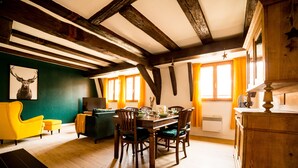 Un coin repas avec une table et des chaises en bois, un canapé vert et un fauteuil jaune.
