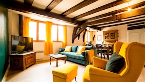 Un salon chaleureux avec un canapé, un fauteuil jaune et un téléviseur posé sur un meuble en bois.