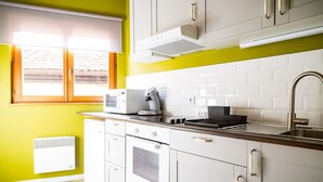 Une cuisine moderne avec des meubles blancs, un four à micro-ondes, une bouilloire et un évier.