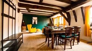Un espace repas comprenant une table et des chaises en bois, un banc et un mur d’accent de couleur verte.