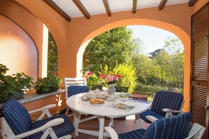 A patio with a round table, striped chairs, and potted plants. - Menaggio Poggio Fiorito Loggetta (Menaggio)