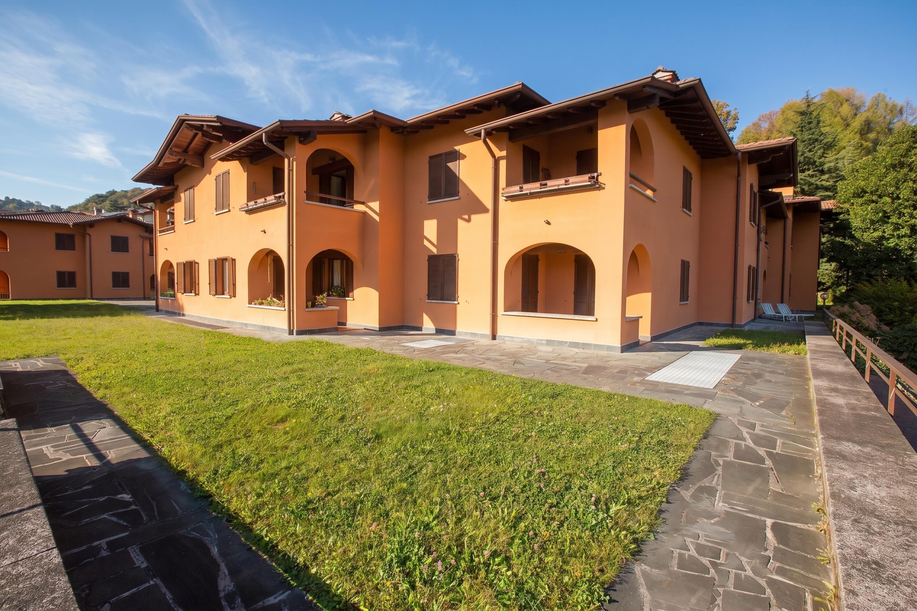 A multi-story building with a flat roof, large windows, and a paved courtyard.