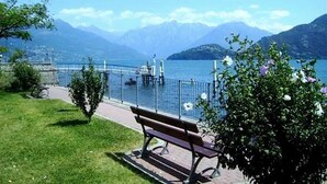 Un banco junto a un paseo lacustre con vistas a montañas y una isla distante.