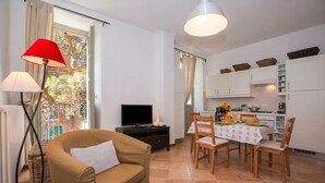 Ein Wohnzimmer mit Sofa, Fernseher und Essbereich mit Tisch und Stühlen.