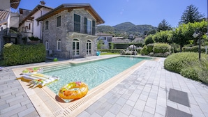 Ein Steinhaus mit Pool, umgeben von viel Grün und Hügeln.