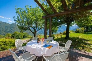 Una mesa al aire libre con vistas a montañas, una pérgola y una botella de champán.