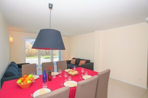 A dining area with a red table set for six, including plates, glasses, and a bowl of fruit. - Villa Intelvi (Cerano d'Intelvi)