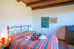 A bed with a striped bedspread, a bedside table with a lamp, and a dresser with drawers. - Villa Intelvi (Cerano d'Intelvi)