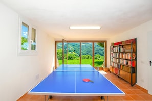 Une pièce avec une table de ping-pong, une bibliothèque et une vue sur la verdure.