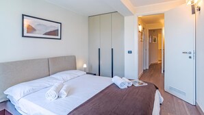 A hotel room with a bed, a framed picture, a wardrobe, and a door. - Sant' Andrea Deluxe (Menaggio)