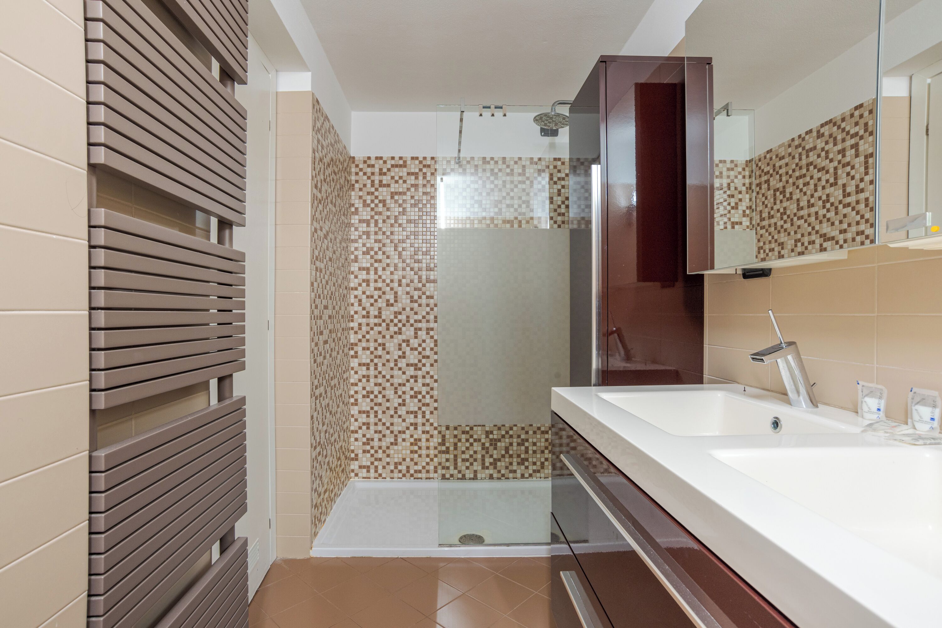 A modern bathroom with a shower, a large mirror, and a vanity with a sink.