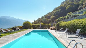 A rectangular swimming pool with a stone border, surrounded by lounge chairs and a stone deck. - Sant' Andrea Deluxe (Menaggio)