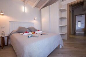 A neatly made bed with pillows, a bedside table with a lamp, and a wall-mounted shelf unit. - Villa Rosalia (Menaggio)