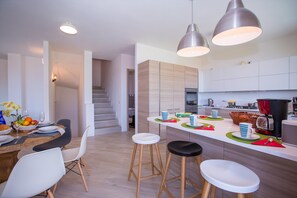 A modern kitchen with a central island, bar stools, and pendant lighting. - Villa Rosalia (Menaggio)