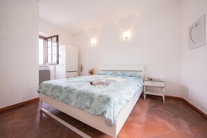 A bedroom with a bed, bedside table, and a window.