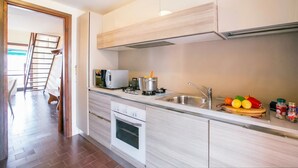 Une cuisine moderne équipée d’un four encastré, d’un four à micro-ondes et d’un évier en acier inoxydable.