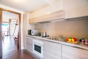 A modern kitchen with a built-in oven, a microwave, and a stainless steel sink.