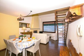 Ein Essbereich mit einem Tisch für vier Personen, einer Couch, einer Treppe und einem Fenster mit Blick.