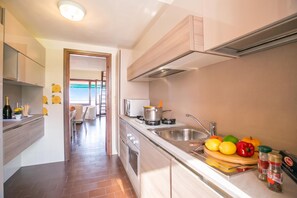 Une cuisine moderne équipée d’une cuisinière, d’un évier et d’un assortiment de fruits et de légumes disposés sur le plan de travail.