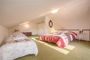Une chambre avec deux lits, une armoire, un miroir et une petite table sur laquelle se trouvent une bouteille et un verre.