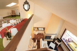 Une chambre d’hôtel comprenant un lit, un canapé, une table à manger, une cheminée et une grande fenêtre.