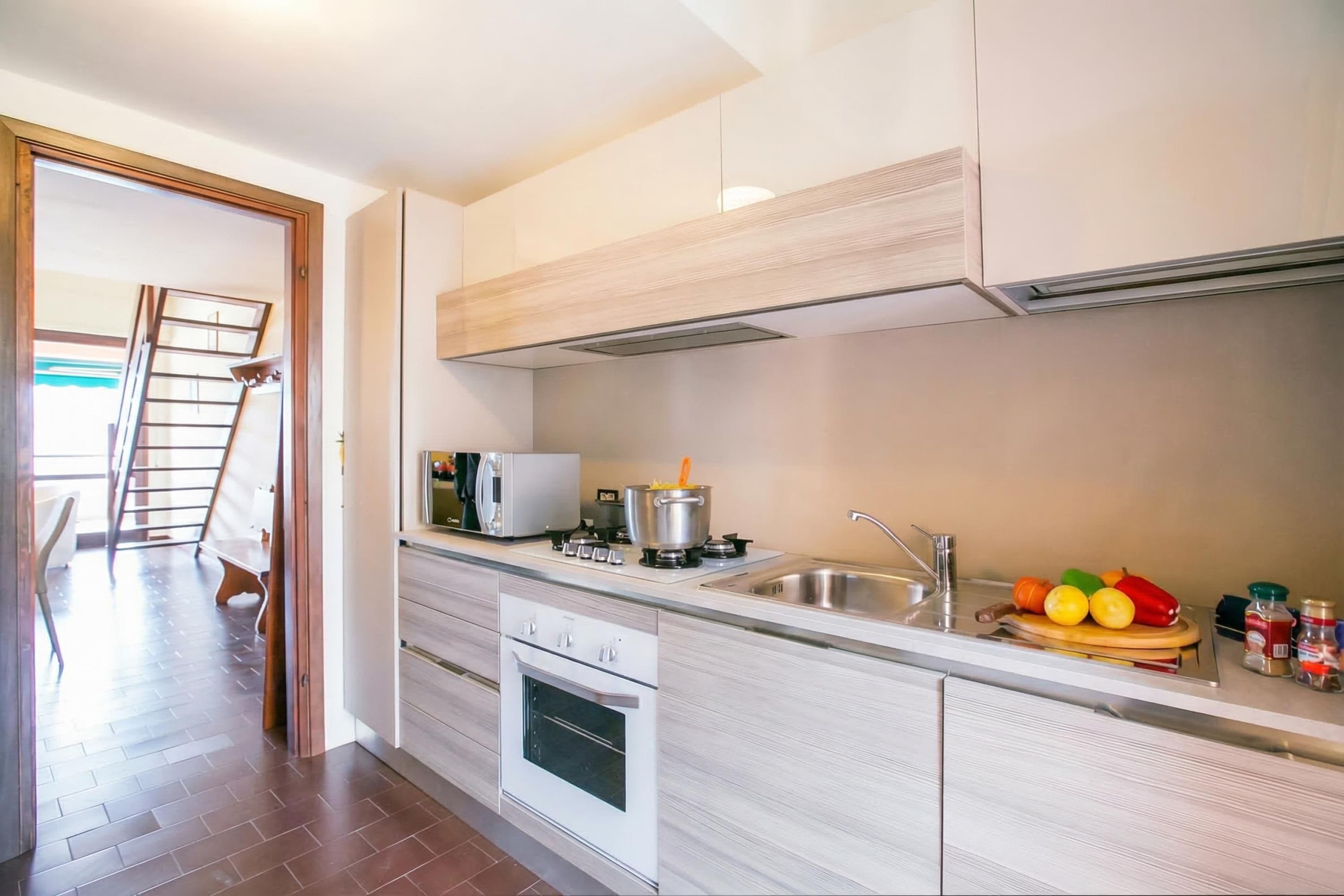 A modern kitchen with a built-in oven, a microwave, and a stainless steel sink.