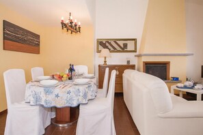 Un comedor con una mesa dispuesta para cuatro, un sofá, una chimenea y un espejo en la pared.