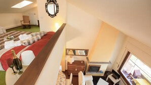 Une chambre d’hôtel comprenant un lit, un canapé, une table à manger, une cheminée et une grande fenêtre.