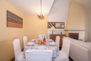 A dining room with a table set for six, chairs, a chandelier, a mirror, and a fireplace. - Cadenabbia Vista Lago (Griante)