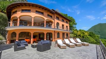 A multi-story building with a curved roof, outdoor seating area, and a balcony.
