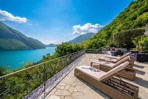 A terrace with outdoor seating and a view of a lake and mountains. - Villa Isola Verde (Valsolda)