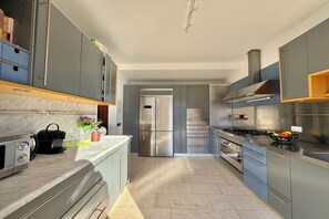 A modern kitchen with grey cabinets, stainless steel appliances, and a marble countertop. - Villa Isola Verde (Valsolda)