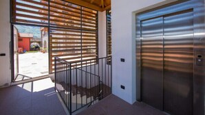 A modern building entrance with a metal gate, a staircase, and a large elevator. - Borgo La Sorgente - Tulipano (Gravedona)