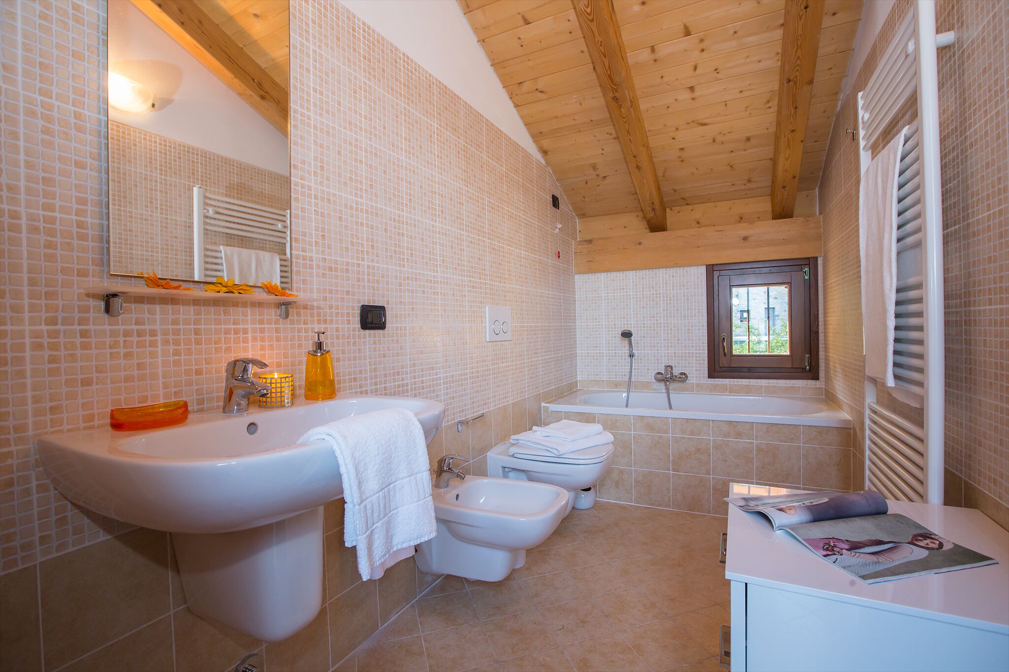 A bathroom with a sink, bidet, bathtub, and a window.