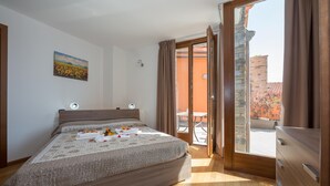 A bedroom with a bed, a painting, a window, and a sliding door to a balcony. - Borgo La Sorgente Erica (Gravedona)