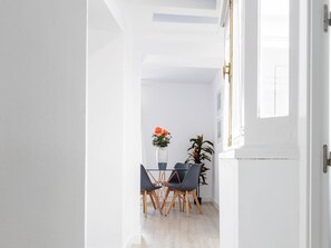 A modern dining area with a table and chairs, a vase with flowers, and a potted plant.