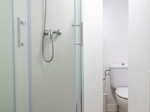 A bathroom with a shower, toilet, and glass door.