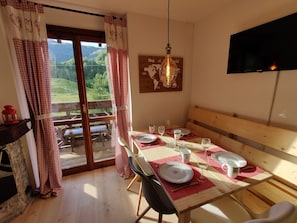 Enjoy meals in this dining area with a wooden table, comfortable bench, and large window offering a view of the surrounding landscape.