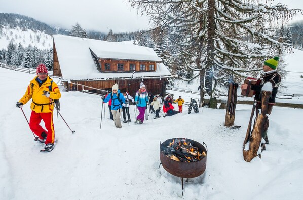 A wooden lodge with a snow-covered roof, surrounded by snow-covered trees and mountains.