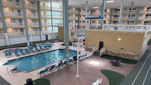 Una piscina interior con sillones de descanso, un asta de banderas y vistas del edificio del hotel.