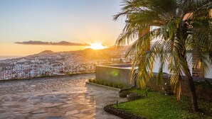 Un sendero empedrado que conduce a un edificio con vistas a un paisaje urbano y una puesta de sol.