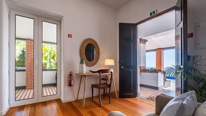 Habitación de hotel con piso de madera, un escritorio con lámpara, una silla y vistas al exterior.