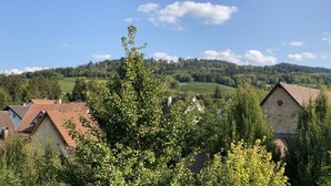 Ein ländliches Dorf mit traditionellen Häusern, einem Hügel im Hintergrund und wolkenlosem Himmel.