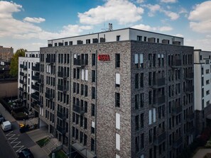 Ein mehrstöckiges Gebäude mit einer Stein-Fassade, mehreren Balkonen und einem Schild, das anzeigt, dass es sich um ein Wohnkomplex handelt.