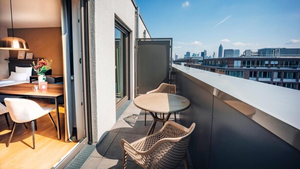 Un balcon moderne doté d’un espace repas, comprenant une table et des chaises, et offrant une vue sur la ville.