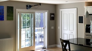 Cocina moderna con puerta de vidrio que da a un patio exterior, una puerta blanca y un comedor con mesa de vidrio.