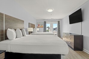 A modern hotel room with a large bed, a TV mounted on the wall, and a view of the outside. - MONTHLY RENTAL - Gorgeous Modern Ocean View Condo w/ Access to Resort Amenities (Myrtle Beach)