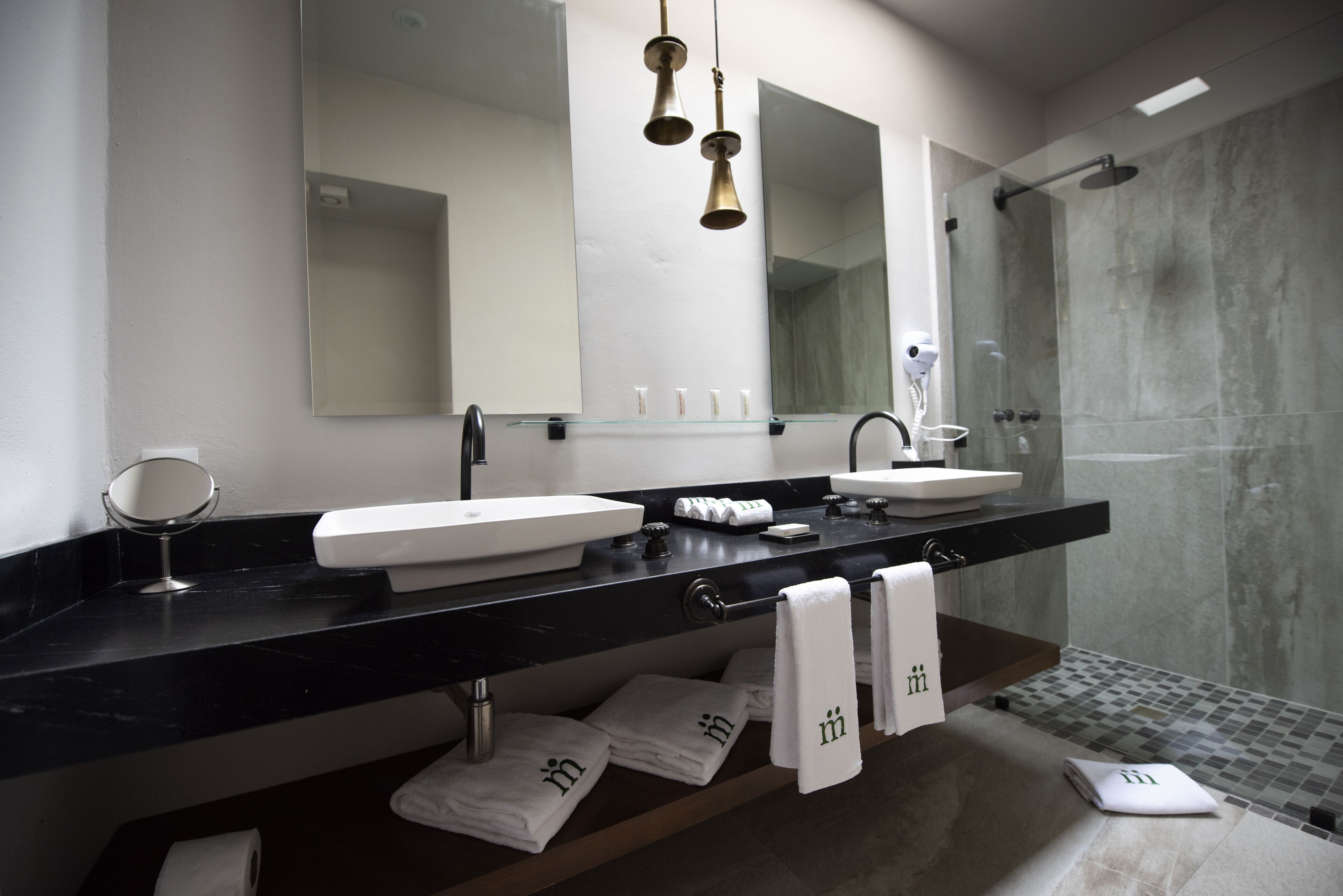 A modern bathroom with two sinks, a large mirror, and a shower area.