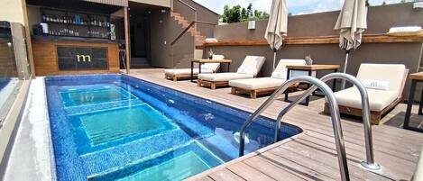 A swimming pool with lounge chairs and a bar area.
