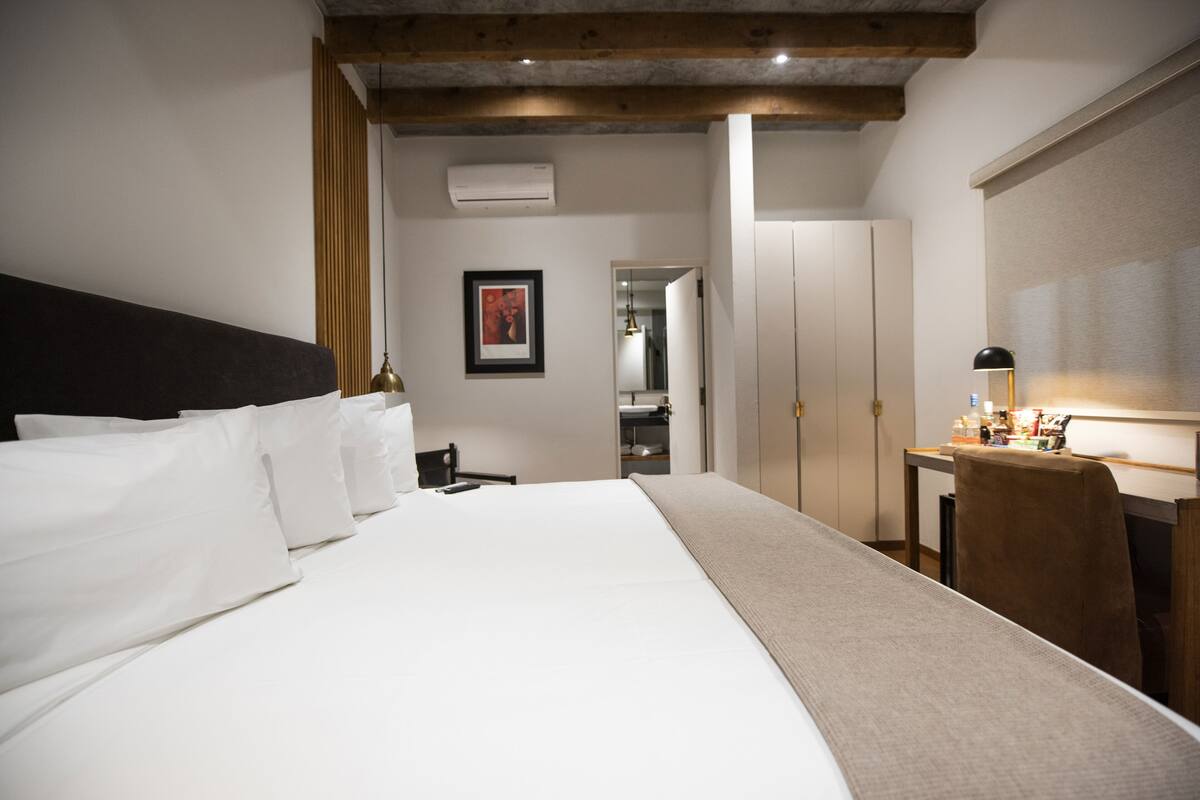 Habitació d'hotel amb un llit gran, un escriptori amb una làmpada i un armari.
